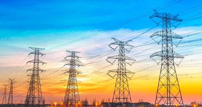 electric transmission lines silhouetted against sunset